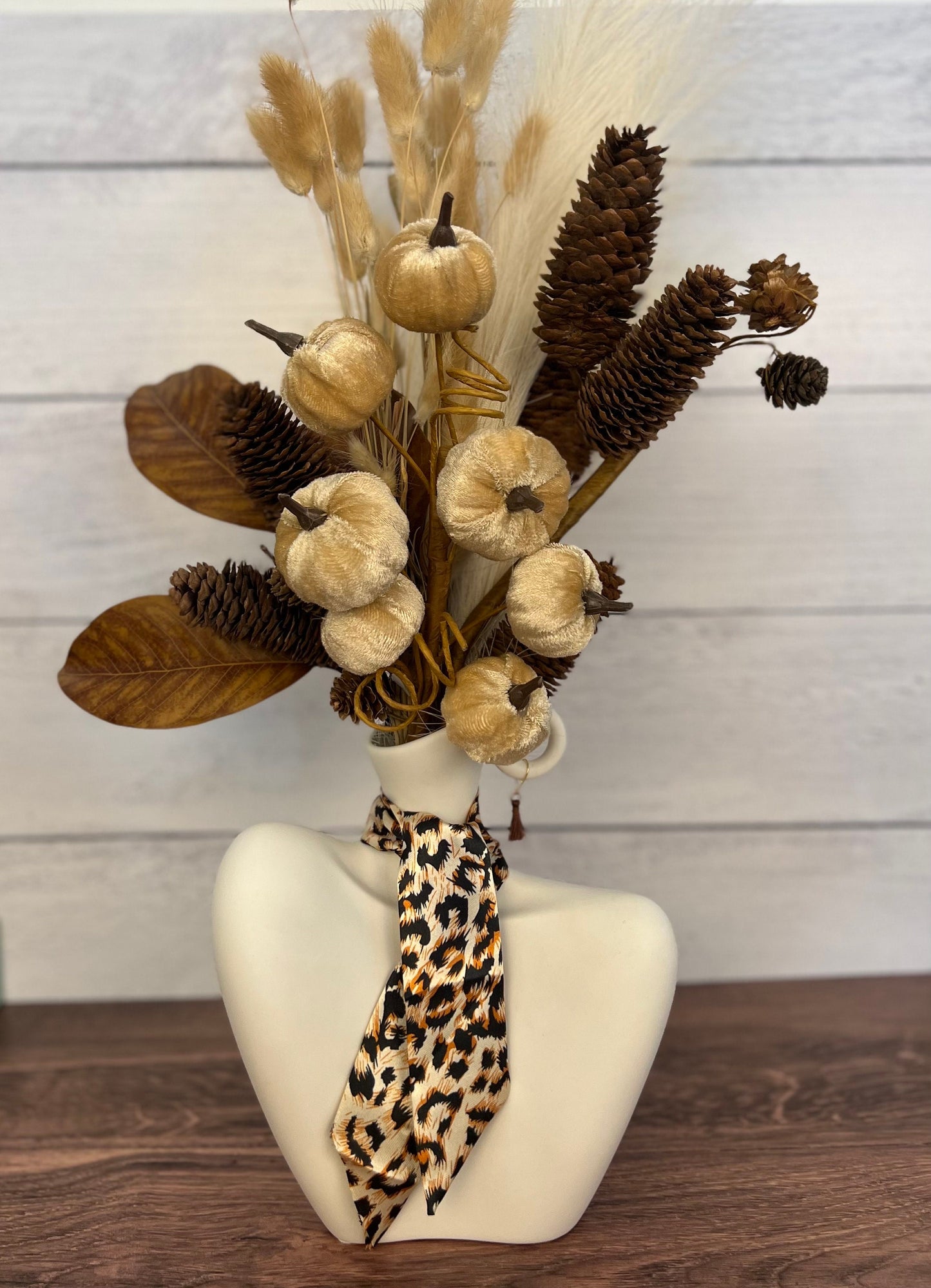 Artificial floral arrangement in a vase. Ceramic centerpiece with faux flowers, and velvet pumpkins. Faux floral arrangement for home decor.